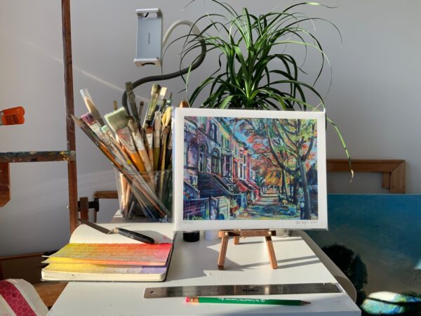 8.5"x11" giclee print on artist's table in studio with pencil, ruler, plant, and brushes in the background