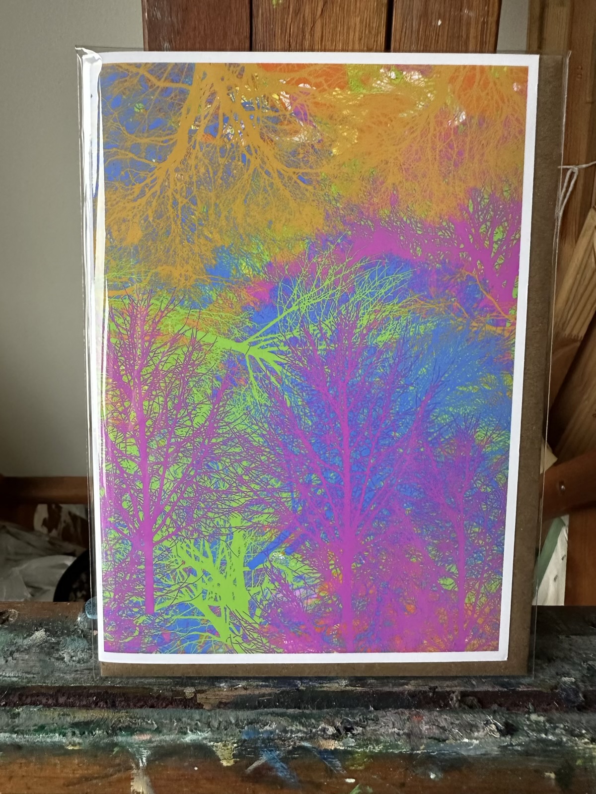 Greeting card showcasing a digital artwork by Noel Hefele from Procreate on iPad, depicting a vivid interplay of neon colors illuminating intricate tree branches.