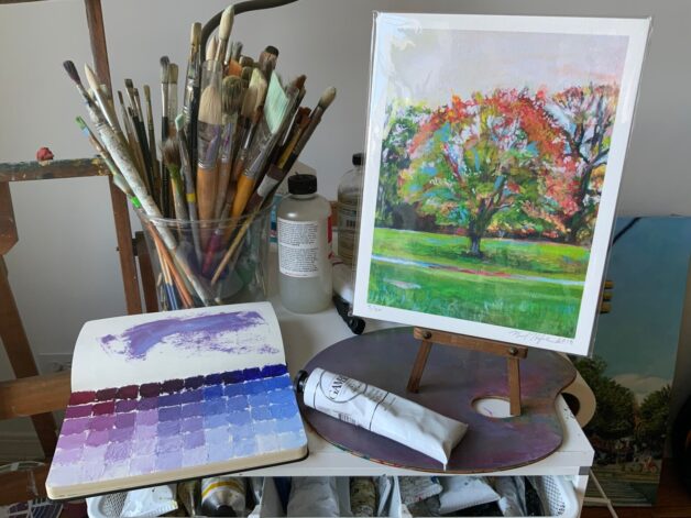 Art studio view with red tree giclée print and painting tools